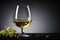 White wine in wine glass, grapes and almond on black background. Commercial promotional photo