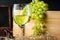 White wineglass and white yellow green bunches of berry grapes with bottle of wine