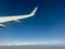 White wing from airplane window on sunny day. Great views of landscape. Aerial view of clouds through a plane window. Wing of