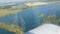 The white wing of a passenger plane against the top view of nature backdrop of a beautiful blue lake, flies over a pond