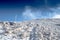 White winter meadow in mountains. Frozen white grass, blue sky