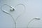 White wired headphones, heart-shaped headset on a silver background.