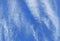 White wispy Cirrus Clouds forming in a vertical direction against a deep blue sky