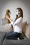 White woman sitting on a sofa in a room with a toy bear in a medical mask, virus protection