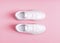 White womens gumshoes on a pink background.