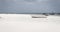 White wooden boat on white sand shallow. Low tide landscape with abandoned white boat. Sailboats on low tide of Indian ocean.