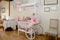 White wooden candy cart decorated with white and pink candy and decorations.