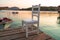 White wooden chair on wooden jetty in the turquoise sea water during sunrise