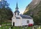 White Wooden Chapel Surrounded By Large Mountains In Undredal At Aurlandsfjord In The Late Afternoon