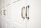 White wooden cupboard doors modern interior, storage or wardrobe closed with metal handles