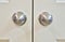 White wooden cupboard doors with silver doorknobs, closeup selective focus.