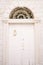 White wooden door on the stone facade of an ancient building with a forged arch