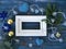 White wooden frame decorated with fir branches, Christmas-tree lighting with snowflakes, felt hearts on a blue wooden textural bac