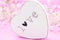 White wooden heart closeup with word Love, on pink mesh fabric and white flowers