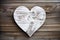 White wooden heart on dark wood plank background. Rustic farmhouse shabby chic backdrop