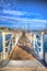 White wooden jetty walkway leading to boats and yachts in a marina