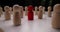 White wooden pawns stand randomly with red figure in center
