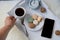 White wooden tray with black tea, coffee, plate with macaroon cakes, alarm clock, blank screen phone, concept of technology, time