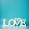 White word LOVE on turquoise blue background, front view. Modern layout or mock up