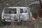 white wrecked minibus car overgrown with gray dry vegetation