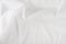 White wrinkled fabric. White fabric with large folds top view. For overlay texture or design.