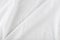 White wrinkled fabric. White fabric with large folds top view. For overlay texture or design.