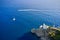 White yacht and motor boat are sailing near a light house in Portofino, Italy. A lighthouse is located on the hill near a seaside