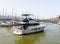 A white yacht with passengers on a sunny day moves from the pier towards the exit to the Mediterranean Sea in the port of Haifa in