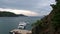 White yacht with people stands near the pier in the bay.