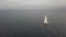 White yacht sailing in sea while golden sunset in cloudy sky drone view