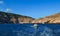 white yacht sails in blue sea among big red stones cliffs, mountains, summer light of sun