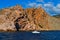 white yacht sails in blue sea near big red stones cliffs mountain, summer sunset, clouds, vacation