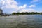 A white and yellow boat sailing through the Savannah river with blue sky and clouds with a tall hotel and the convention center