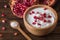 White yogurt with pomegranates in wooden bowl on rustic table.