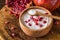 White yogurt with pomegranates in wooden bowl on rustic table.