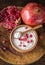 White yogurt with pomegranates in wooden bowl on rustic table. T