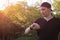 A white young man or adult guy in casual wear is looking at his watch in a city green park. The concept of expectation