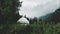 white yurt, a nomad house in a mountain forest meadow among grass and flowers in rainy and foggy weather