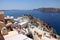 Whitewashed buildings and the ruins of Castle of Agios Nikolaos on the edge of the caldera cliff, Oia village