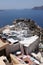 Whitewashed buildings and the ruins of Castle of Agios Nikolaos on the edge of the caldera cliff, Oia village, Santorini