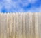 Whitewashed wood privacy fence with blue sky and clouds