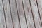 A whitewashed wooden surface worn out due to weather. Planks painted white. The texture of the wooden board