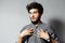 Who, me? Portrait of bearded young stricken guy with disheveled hair isolated on grey background.