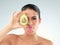 Who needs expensive moisturizer when youve got avocado. Studio portrait of a beautiful young woman covering her eye with