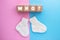 WHO text on wood cubes and pair of cute knitted socks on pink-blue background. Gender of the baby. Boy or girl. Waiting foa a