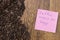 Whole aromatic coffee beans on a wooden background closeup with a note.