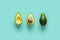 Whole avocado fruit and two halves in a row  on blue background