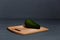A whole avocado on a wooden cutting board