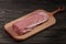 Whole boneless pork loin without fat. Pork tenderloin on a cutting board on a dark background