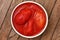 Whole canned tomatoes in pottery dish from above.